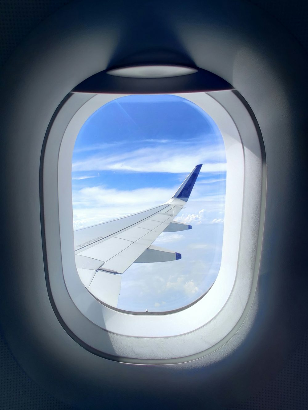 View from an airplane window over the wing, flying above the clouds